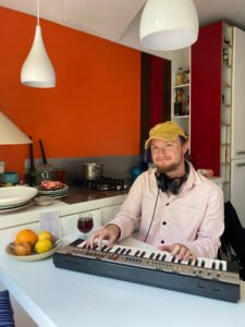 Aaron King sitting next to his keyboard wearing headphones around his neck